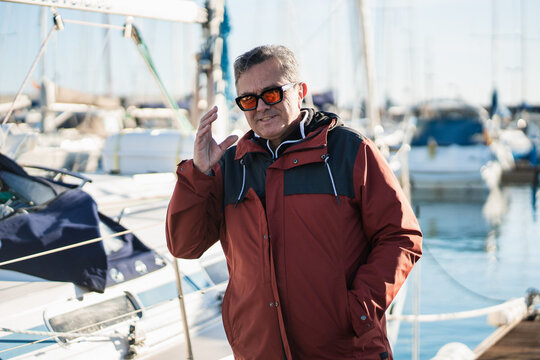 Man wearing sunglasses at marina with yachts