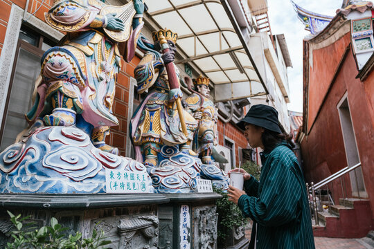 Person viewing colorful buddhist statues in old taiwan temple