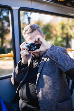 Man taking pictures with vintage camera on bus tour