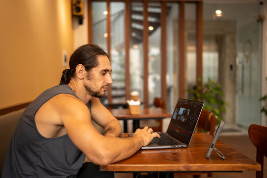 Man working on laptop, editing video in cafe