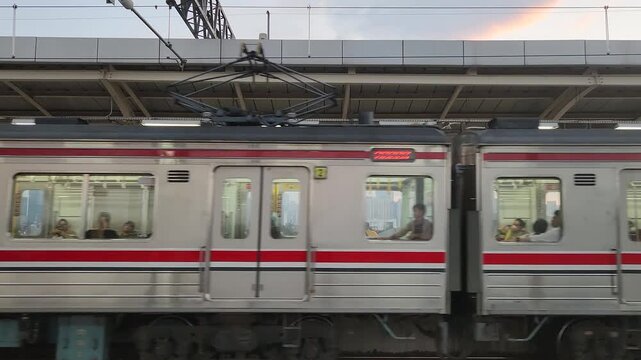 KRL commuter train moving along the railway in an urban setting with daily transportation activity. Perfect for travel, public transport, and city lifestyle themes.