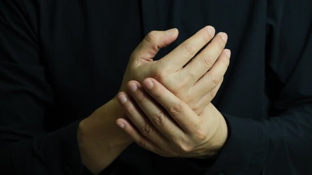 A man holding their painful hand and numbness, illustrating the concept of joint pain, injury, or inflammation, highlighting the importance of medical attention, proper care, and orthopedic recovery.