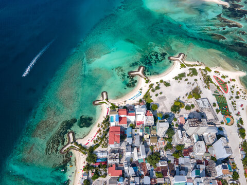 Aerial drone view of beachfront hotels and private beach at Maafushi island in Kaafu Atoll, Maldives.