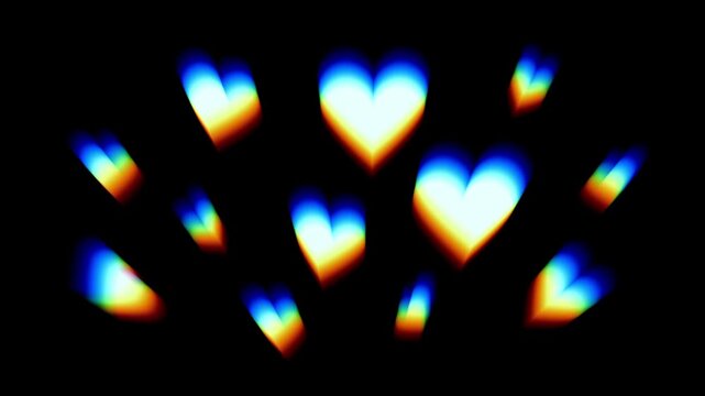 A cluster of colorful rainbow toned heart shaped light bokeh glows warmly scattered together creating a festive romantic scene on a black background