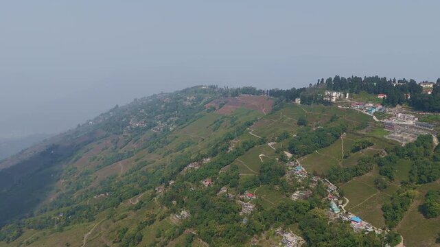 A stunning 4K drone view of a peaceful village near Mirik, Darjeeling, featuring lush farmland, green landscapes, and a winding zigzag village road surrounded by scenic Himalayan beauty.