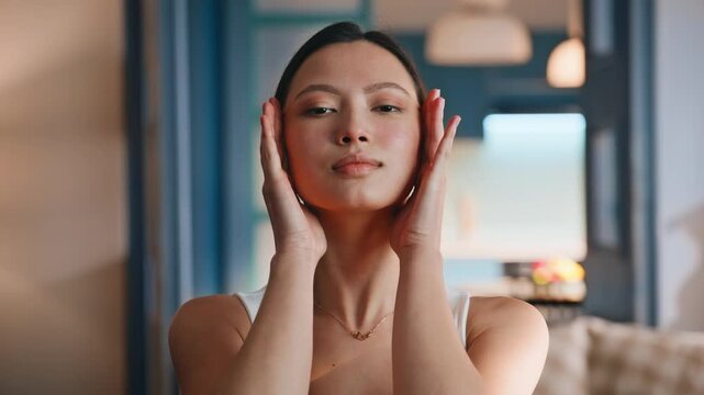Young woman doing facial massage at home. Close up beauty skincare portrait.