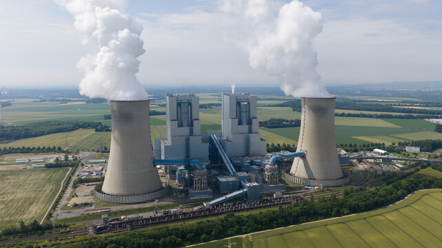Aerial view of RWE Power AG Kraftwerk Neurath, BOA 23, a power plant with cooling towers emitting steam, surrounded by agricultural fields in Grevenbroich, Nordrhein-Westfalen, Germany.