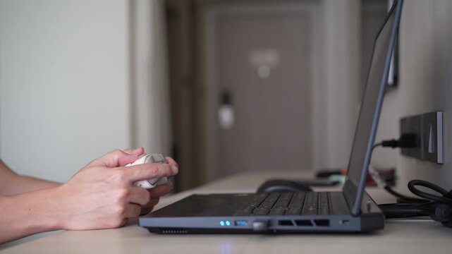 Closeup people hand or gamer holding joystick or gaming controller to enjoy playing game on computer notebook or laptop console and clenching fist or fistful victory fun and win satisfy with joy stick
