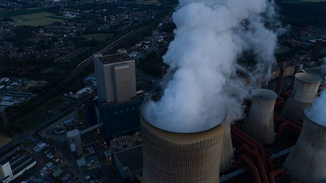 Aerial view of Kraftwerk Niederaussem with large cooling towers emitting steam plumes over the industrial facility in Bergheim, Nordrhein-Westfalen, Germany.