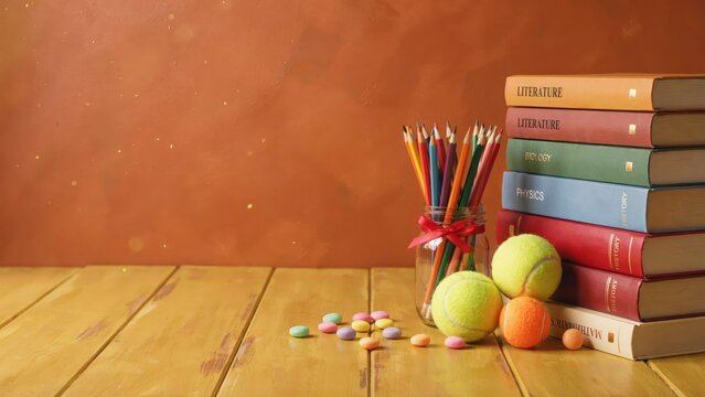 Stack of colorful educational books with pencils and tennis balls
