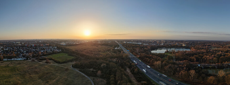 Aerial view of Hanover Langenhagen Silbersee at sunset, featuring the surrounding forest, urban landscape, and a highway in Hanover, Lower Saxony, Germany.