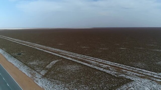 Sweeping aerial panorama of desert salt marsh with road-like lines crossing the surface.