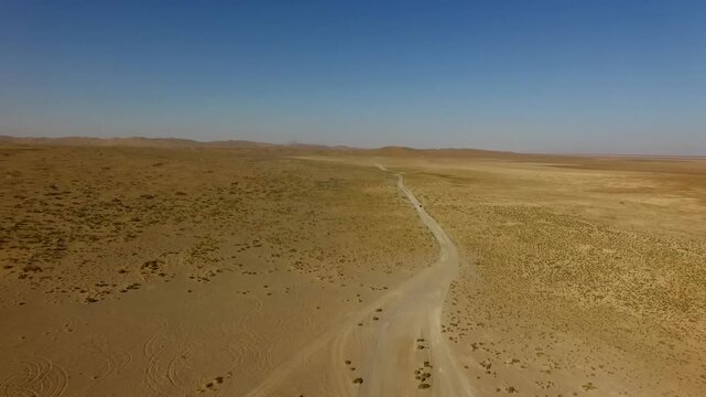 High quality aerial shot of endless desert plain with faint winding path.