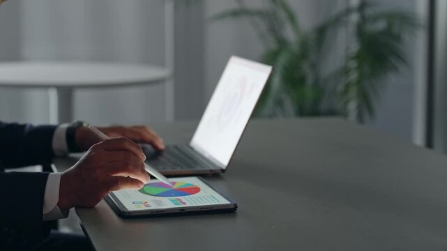 ノートパソコンとタブレットPCを使って作業する男性ビジネスパーソン。オフィス、ビジネス、デスクワーク