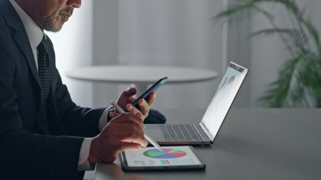 スマホとタブレットPCを使って作業する男性ビジネスパーソン。アプリ、クラウド、AI、DX、ビジネス
