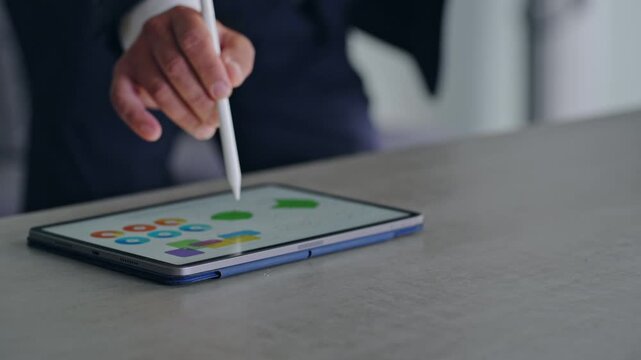 タブレットPCを使って作業する男性。DX、IT、ペン、操作、画面、仕事、作業、デザイン、制作、グラフ