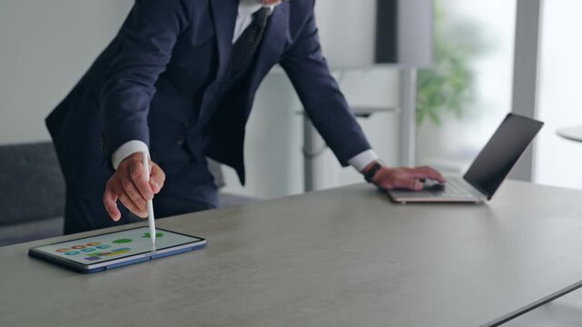 ノートパソコンとタブレットPCを使って作業する男性。ビジネス、DX、AI、IT、仕事、オフィス、操作