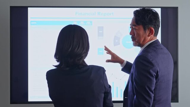 画面を見ながら会話するビジネスパーソンのグループ。会議、チームワーク、同僚、人材、相談、研修、指導