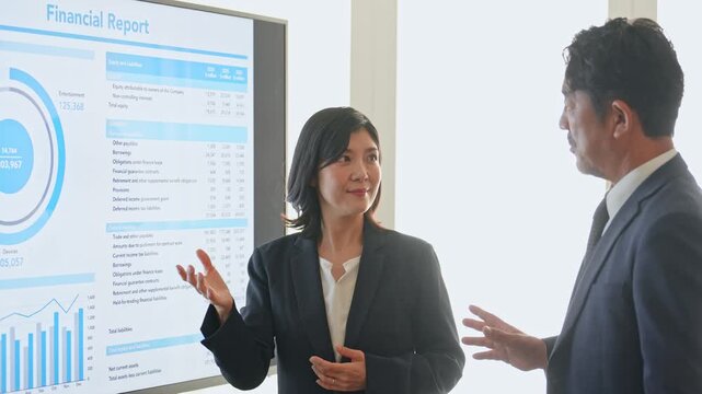 画面を見ながら会話するビジネスパーソンのグループ。会議、チームワーク、相談、提案、商談、プレゼン
