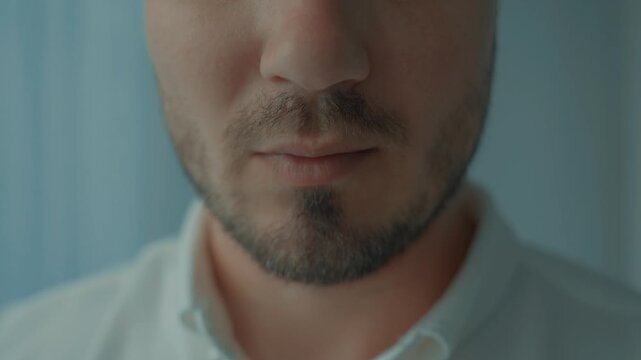 A handsome man's mouth in close-up drinking from a cup of coffee or tea. The lips of a handsome young man. A cup with a drink is leaning against the man's lips.