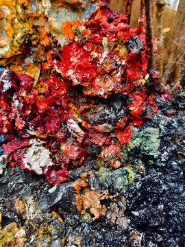 Vibrant messy artist palette covered in glossy paint, scattered brushes and tubes, dried paint