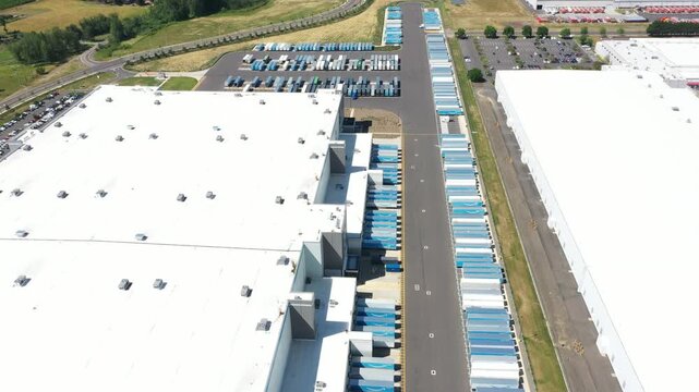 4K aerial drone footage of a major ecommerce fulfillment center in Woodburn, Oregon, USA showing warehouse buildings, truck trailers, loading docks, and large-scale logistics operations