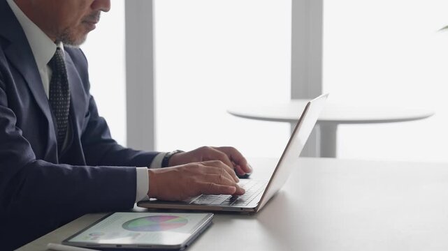 A man working with a laptop and a tablet PC. DX, IT, work, office tasks, desk work, operations.