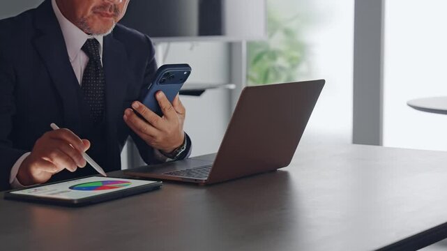 スマホとタブレットPCを使って作業する男性。アプリ、ビジネス、DX、検索、AI、SNS、クラウド