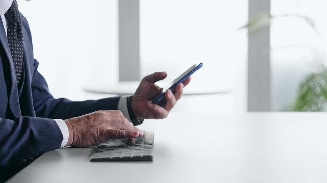 スマホとPCを使って作業する男性ビジネスパーソン。アプリ、SNS、ビジネス、クラウド、ERP、DX