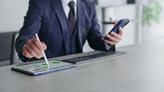 スマホとタブレットPCを使って作業する男性。アプリ、SNS、DX、IT、ビジネス、テクノロジー、AI