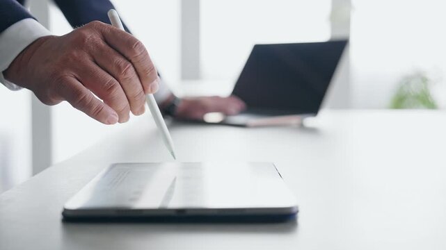 ノートパソコンとタブレットPCを使って作業する男性。DX、IT、ビジネス、オフィス、タッチペン、作業