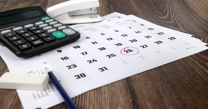 Scenic horizontal tracking view of financial auditing tools including desk calendar with red tax text mark and office calculator