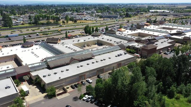 4K aerial drone footage of a busy outlet shopping center in Woodburn, Oregon, USA during the Juneteenth holiday with crowded parking lots, retail stores, and shoppers