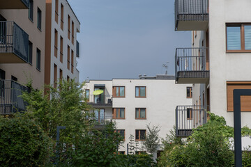 Obraz premium serene residential buildings with balconies and windows in an urban residential area at ground level featuring concrete, metal, and glass materials and greenery.