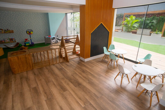 Modern colorful children playroom with wooden furniture, small tables, and indoor playground equipment