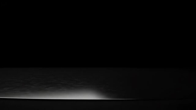 minimalist conceptual background with a subtle light sweep illuminating a dark textured surface in a pitchblack void