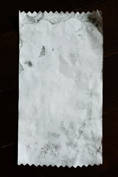 Dirty textured receipt paper with zigzag torn edge isolated on black wooden background with clipping path