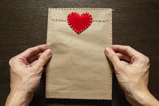 Love letter envelope decorated with stitched heart in men's hand