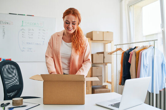 Young woman packing order box in online clothing store