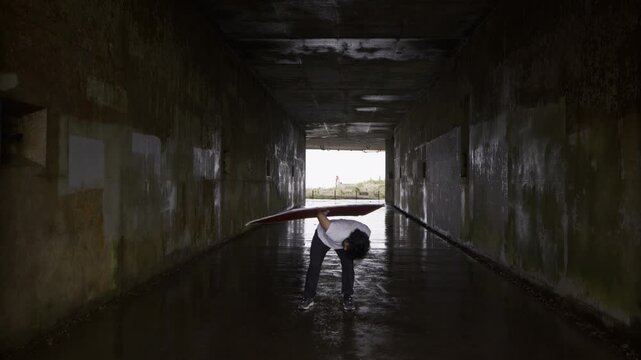 Professional Athlete Spinning Large Painted Board Inside Wet, Concrete Tunnel In San Francisco - Steady Cam Shot