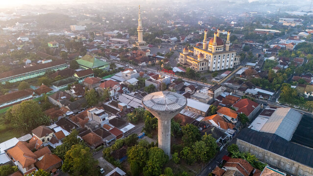 Kecamatan Klaten Utara, Jawa Tengah, Indonesia - 02 July 2026: Aerial view of Al Aqsha Great Mosque Klaten, dense residential rooftops, and a concrete water tower.