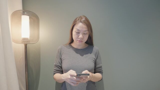 A woman interacts with her smartphone in a modern, minimalistic space, highlighting the blend of technology and daily life.