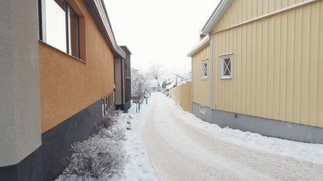 A tranquil winter scene showcasing a snow-covered street lined with colorful buildings, offering a serene glimpse into a charming neighborhood.