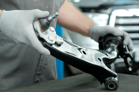 Car service center.Car suspension repair. The lever is front right.New. The car mechanic monitors the serviceability of the spare part.Preparation of the product for installation.