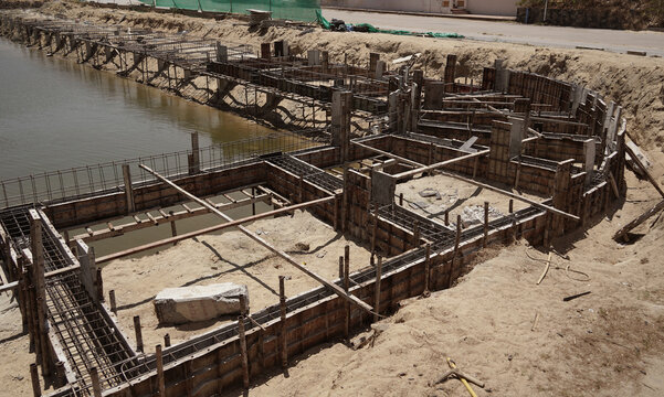 Building process city levee. Exposed foundation rebar grid at site, standing formwork and concrete footings