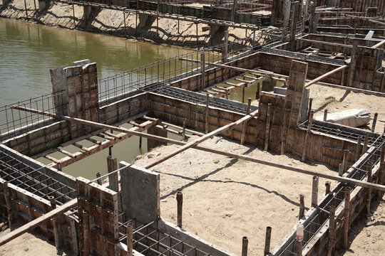 Building process city levee. Exposed foundation rebar grid at site, standing formwork and concrete footings