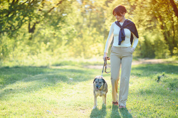 Fototapeta premium Woman and dog enjoying a walk in park