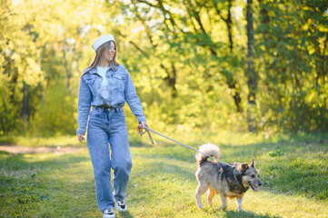 Fototapeta premium Young woman walking dog in sunny park