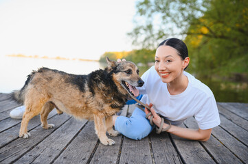 Fototapeta premium Woman smiling, petting dog on wooden pier