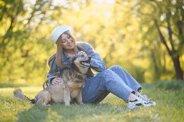 Fototapeta premium Young woman petting dog in park at sunset